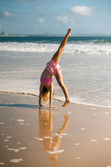 Girl doing a cartwheel on the beach in quick-dry pink striped hybrid boardshorts with No Flash Technology™