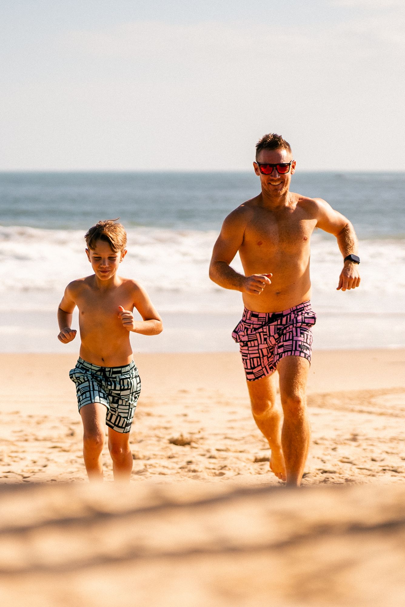 Man and child wearing Pink Geo hybrid lined boardshorts designed for beach and outdoor adventures