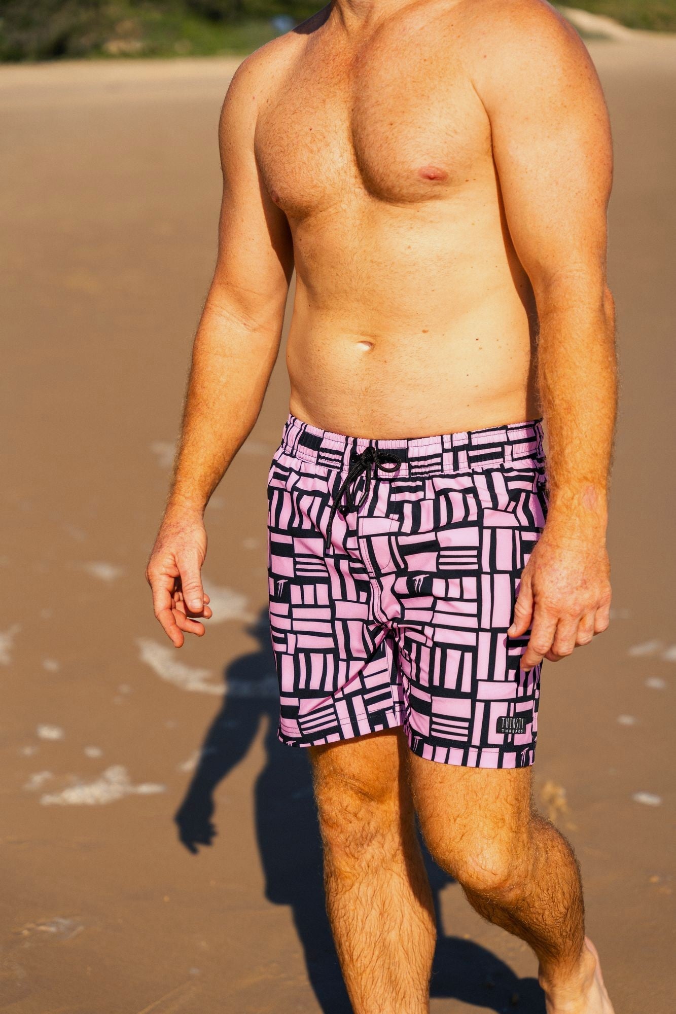 Man wearing Pink Geo quick dry 4-way stretch boardshorts with built-in Hybrid anti-chafe liner at the beach