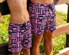 Man and boy wearing matching Thirsty Threads pink geometric hybrid lined boardshorts at beach entrance.